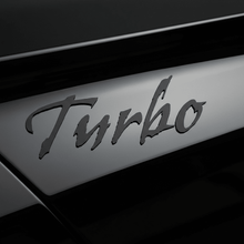 Load image into Gallery viewer, Close-up of black Gothic Turbo sticker on gloss black panel
