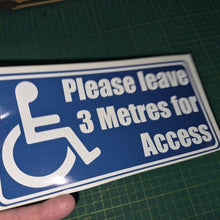 Load image into Gallery viewer, Handheld sign with wheelchair icon and text 'Please leave 3 Metres for Access' on a green cutting mat.