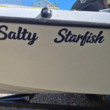 Load image into Gallery viewer, Beige boat with 'Salty Starfish' text on a gravel surface. custom Australian made boat stickers