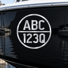 Load image into Gallery viewer, Silver cut-vinyl round boat registration decal on a black boat hull