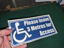 Load image into Gallery viewer, Hand holding a sign with a wheelchair icon and text on a green cutting mat.