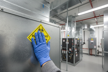 Load image into Gallery viewer, Technician applying sticker to HVAC duct