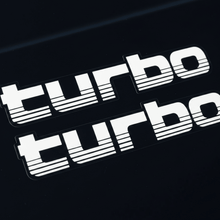 Load image into Gallery viewer, White 100 Series Turbo stickers macro close-up black background