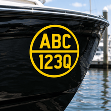 Load image into Gallery viewer, Yellow cut-vinyl round registration decal on a black boat hull