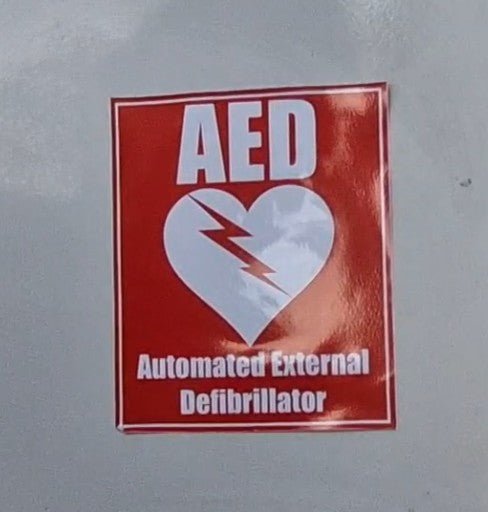 AED sticker on a wall with a red background and white text.