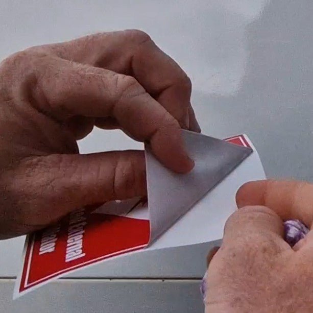 Person peeling a red and white label off a surface
