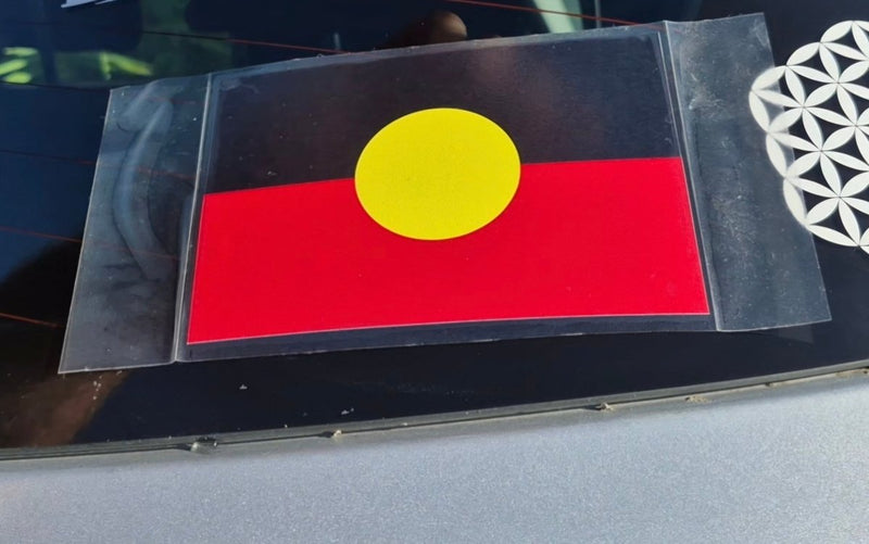 Flag with a yellow circle on a red background, placed on a reflective surface.