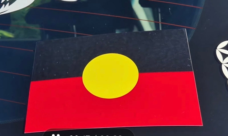 Flag with a yellow circle on a black and red background, placed on a reflective surface.