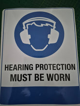 Load image into Gallery viewer, Sign with a hard hat icon and text 'Hearing protection must be worn' on a blue and white background.

