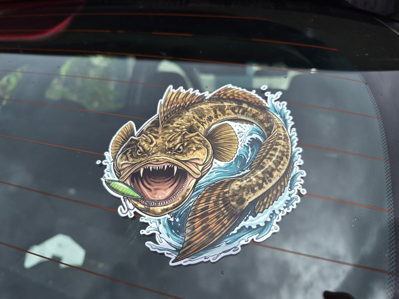 A die-cut vinyl sticker of a detailed flat head fishing lure graphic, shown applied to the rear window of a car.