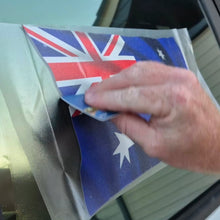 Load image into Gallery viewer, Hand applying an Australian flag decal to a car window.
