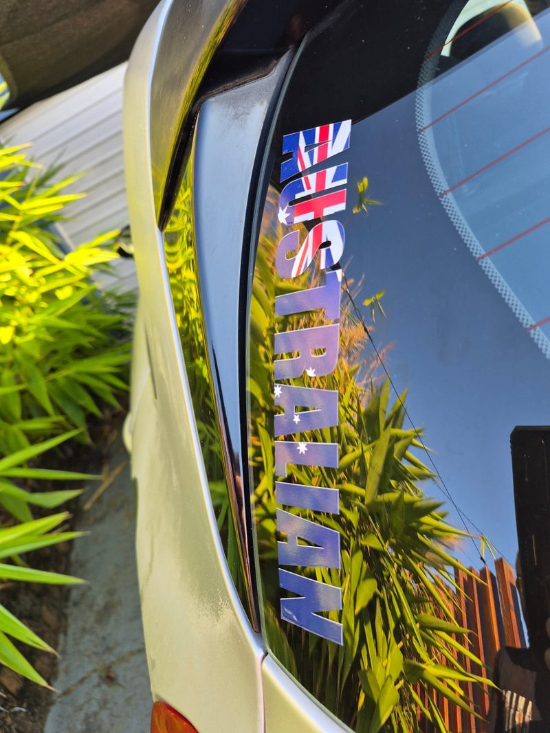 Car with 'AUSTRALIAN' text and Australian flag on a reflective surface with plants in the background