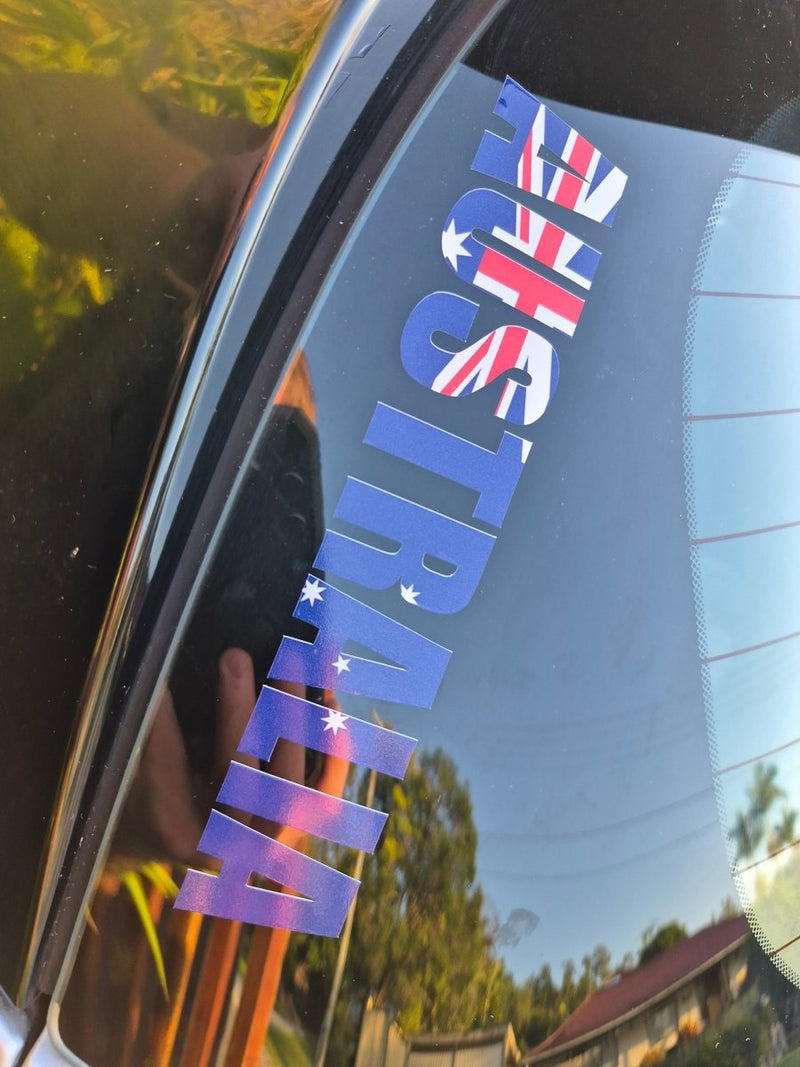 Reflective 'AUSTRALIA' decal with Australian flag colors on a car window.