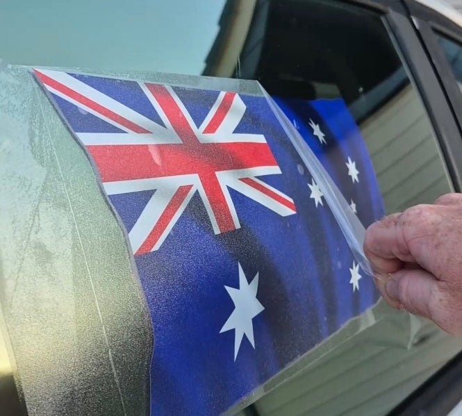 Person applying an Australian flag decal to a car window