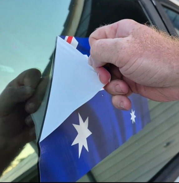 Person holding an Australian flag decal near a car window
