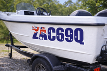Load image into Gallery viewer, White boat with registration number C69Q on a trailer
