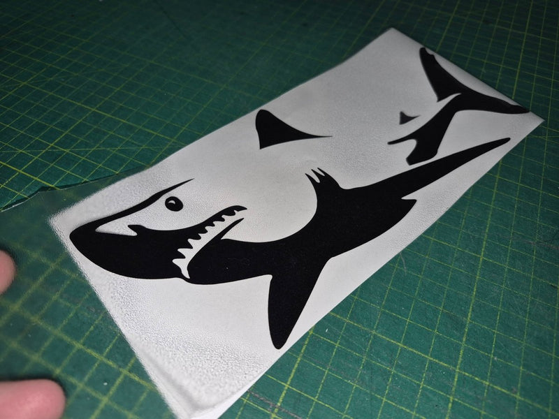 Black shark decal on a white sheet with a green cutting mat background