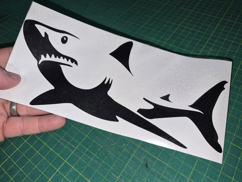 Black shark decal on a white card held over a green cutting mat
