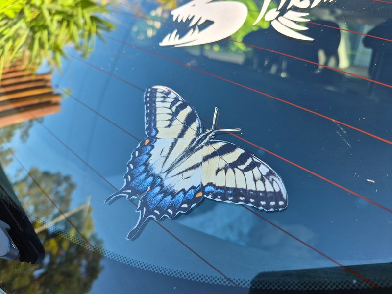 Butterfly decal on a car window with trees in the background