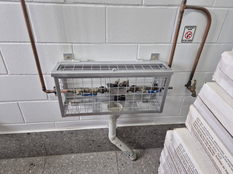 Metal stand with wire mesh top against a tiled wall