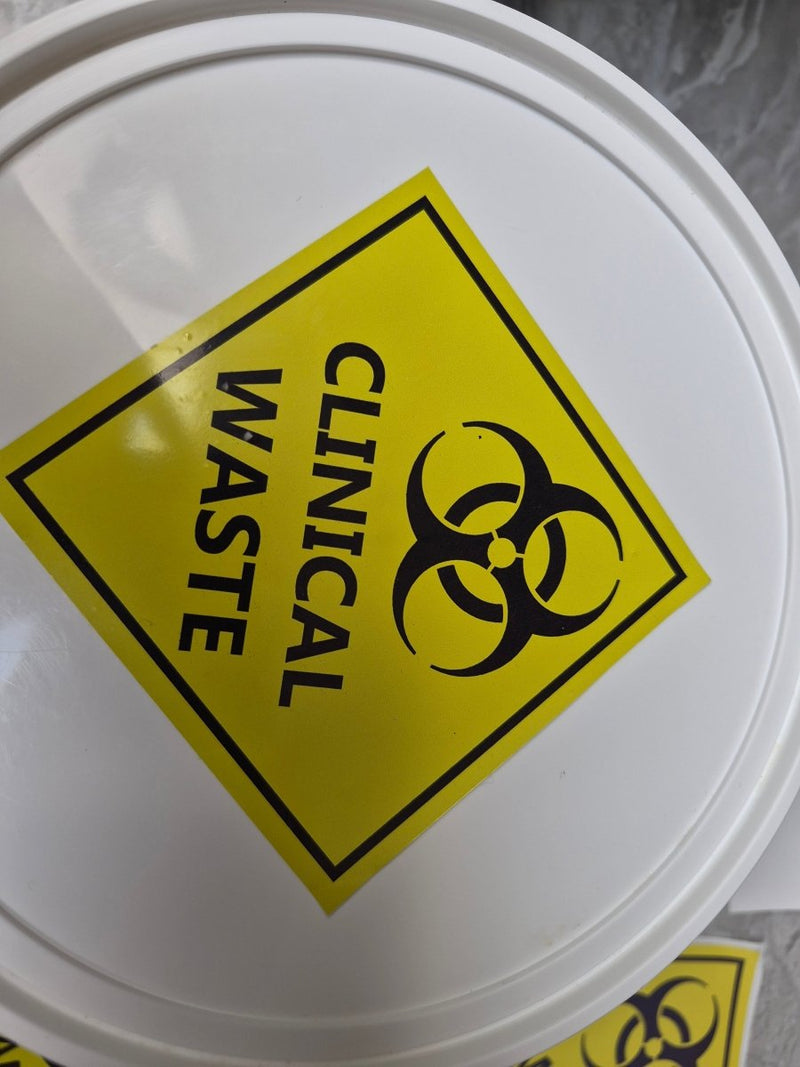 White container with a yellow 'Clinical Waste' sign featuring a biohazard symbol.