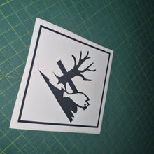 Load image into Gallery viewer, Black and white sticker with tree and bird design on a green cutting mat

