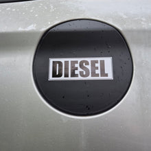 Load image into Gallery viewer, A close-up of a silver car's fuel door featuring a circular black badge with the word 'DIESEL' in white letters.
