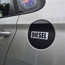 Load image into Gallery viewer, A close-up of the side of a silver car showing a black circular fuel door badge with the word 'DIESEL' in white text. A small Australian flag sticker is visible on the rear window.
