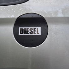 Load image into Gallery viewer, A close-up of a silver car's fuel door featuring a circular black badge with the word 'DIESEL' in white capital letters.
