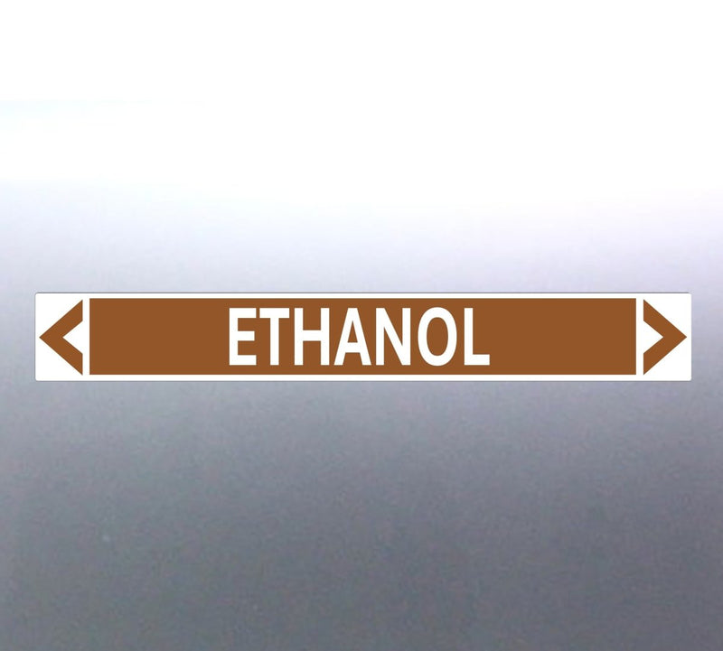 A pipe marker label with the word 'ETHANOL' in bold black lettering on a golden tan background with a white border and green directional arrows pointing in both directions.