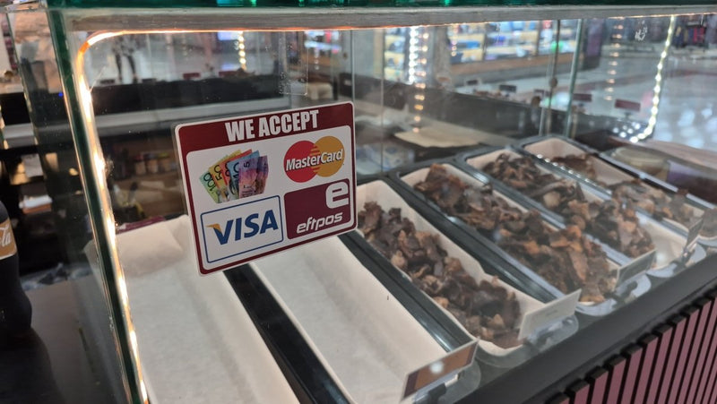 Display case with food items and a sign indicating accepted payment methods.