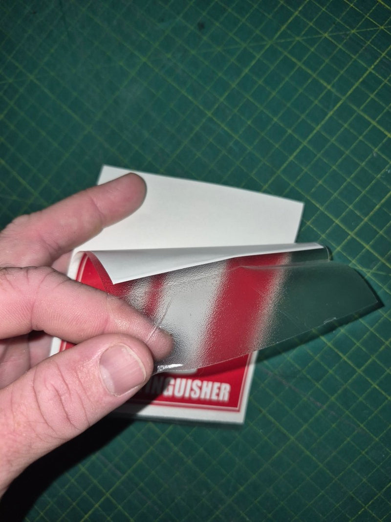 Hand holding a small book or card with a red cover against a green grid background