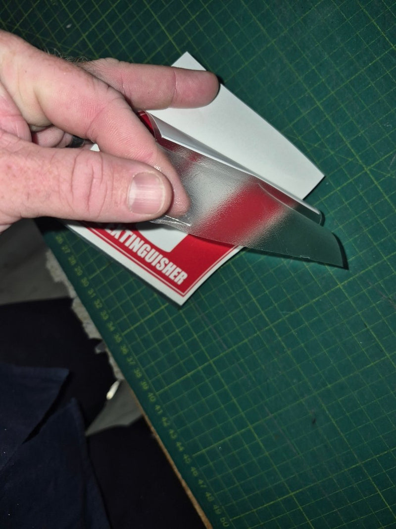 Hand holding a small metallic object on a green cutting mat with a visible brand name.