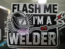Load image into Gallery viewer, Sticker with a welding helmet and text 'Flash me I'm a welder' on a reflective surface.
