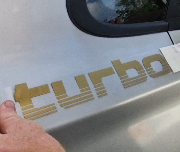 Gold 'turbo' decal being applied to a car door