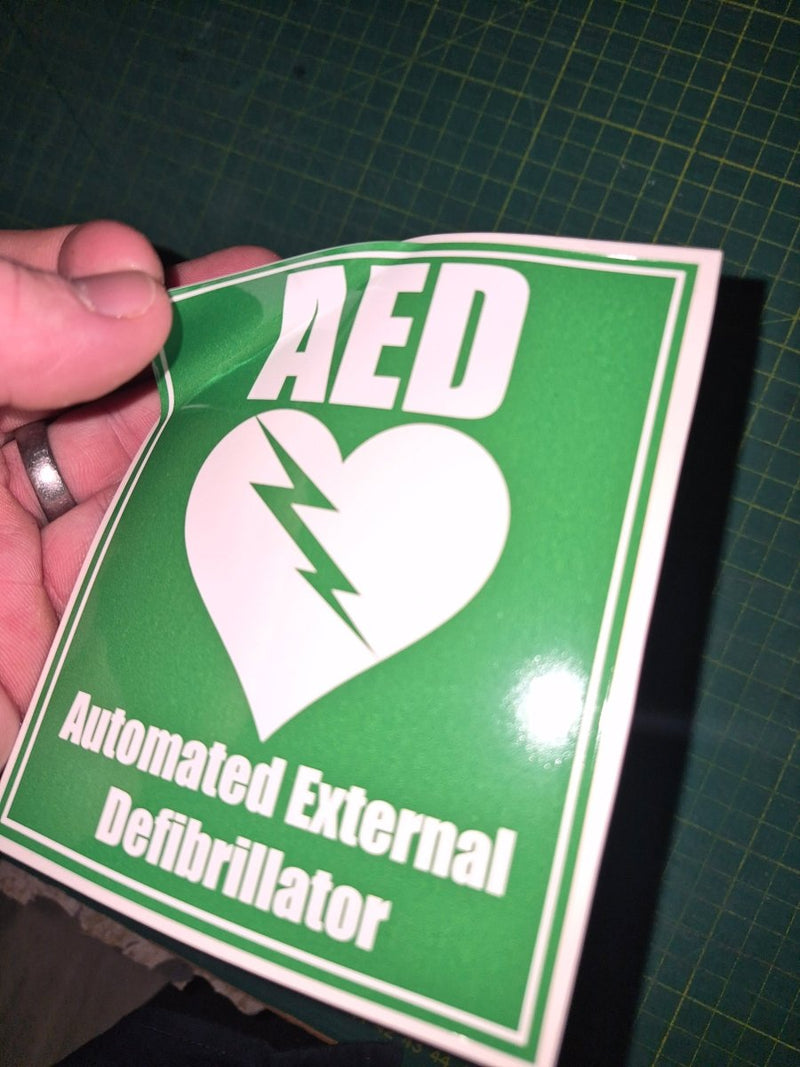 Green sticker with white text and logo on a cutting mat background