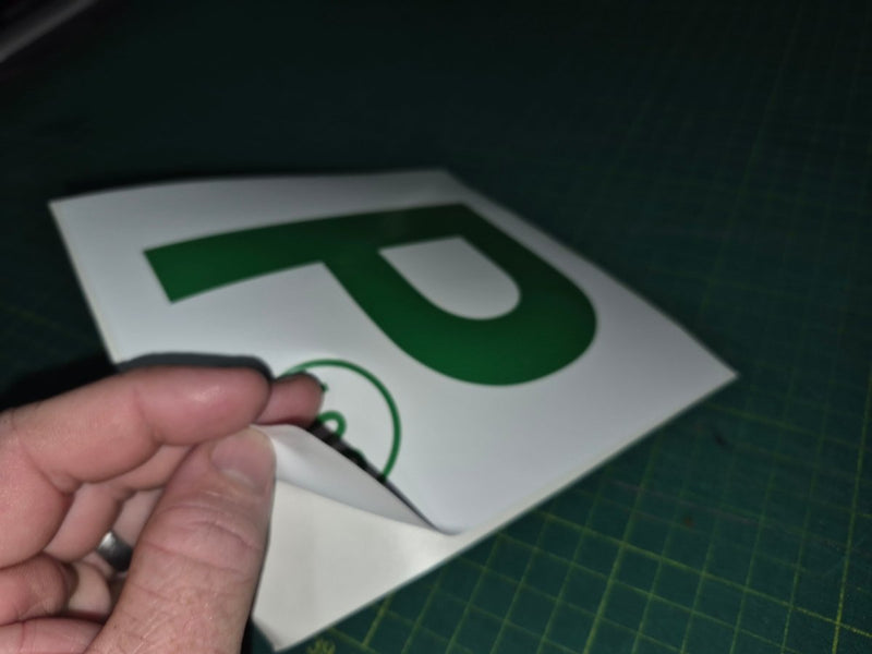 Hand holding a small white object with a green logo on a dark background
