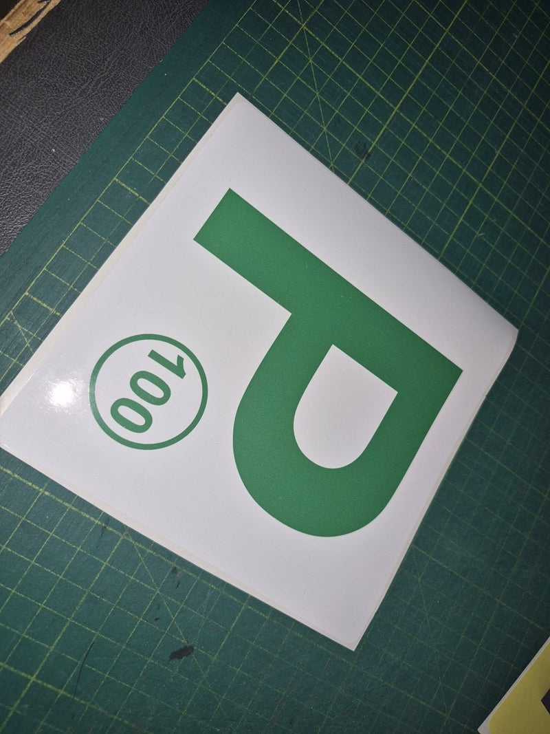 Green 'P' with number 100 on a white background on a green cutting mat.