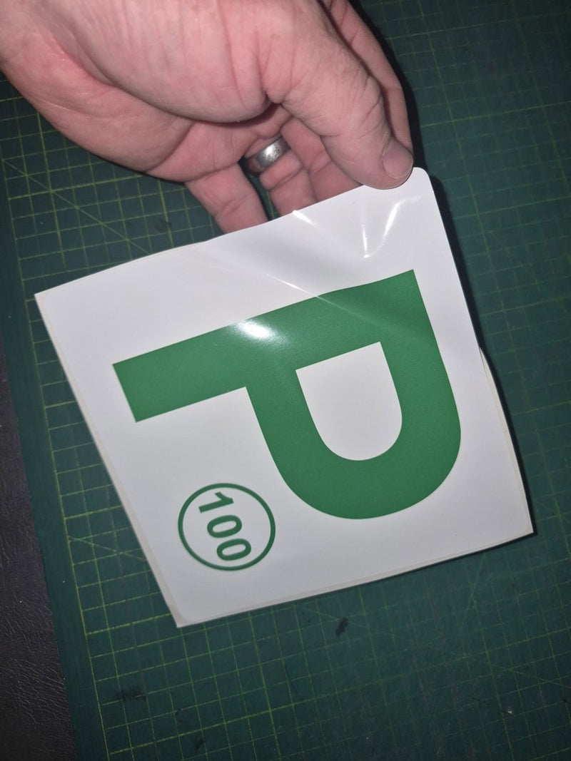 Hand holding a green 'P' with a number 100 on a white background