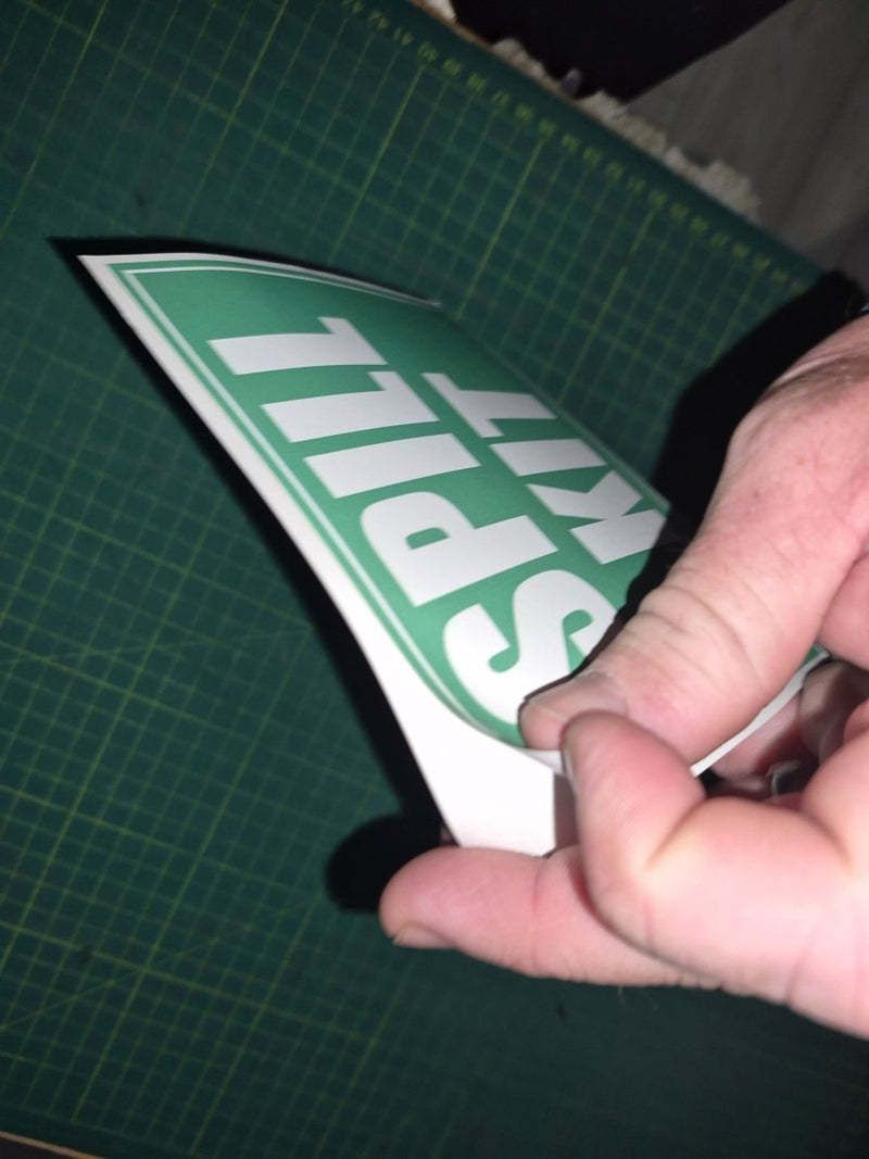 Hand holding a 'Spill Kit' sign on a green cutting mat.