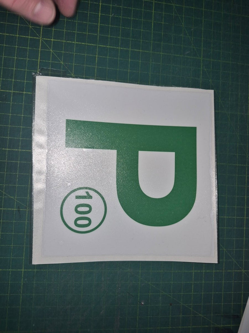 Green 'P' with number 100 on a white background on a green cutting mat.