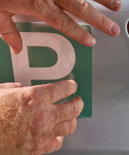 Load image into Gallery viewer, Hand placing a green license plate with a white 'P' on a vehicle.
