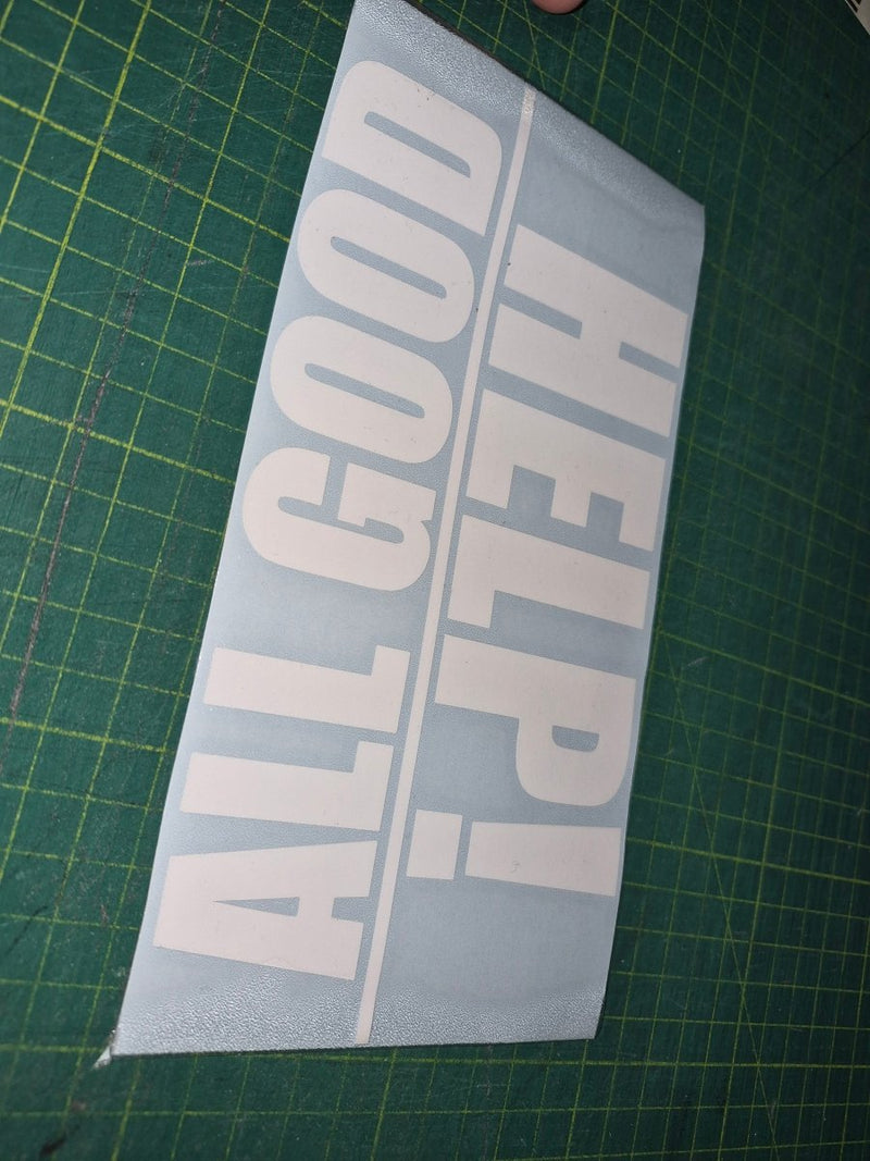 White decal with 'HELP! ALL GOOD' text on a green cutting mat