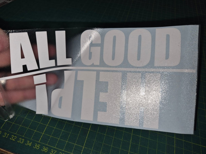 Decal with 'ALL GOOD THINGS' text held over a cutting mat