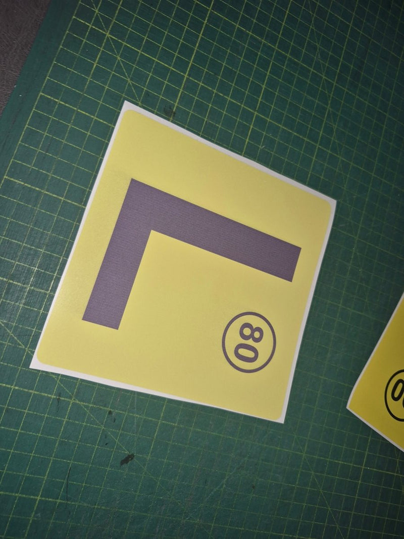 Yellow square with a purple 'L' and black number '80' on a green grid background