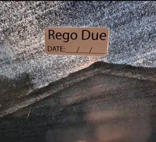 Load image into Gallery viewer, Label with 'Rego Due' text on a textured fabric background
