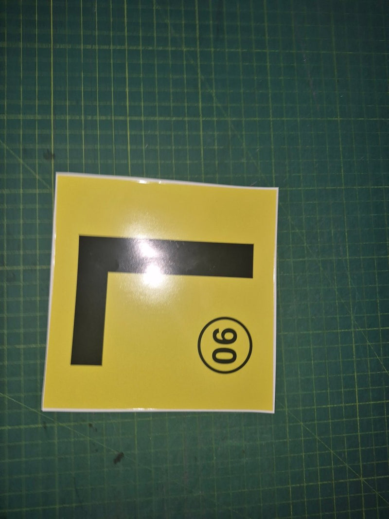 Yellow square with black 'L' and black circle with number 90 on a green grid background
