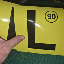 Load image into Gallery viewer, Yellow sign with a black 'L' and number 90 held by a hand on a green cutting mat.

