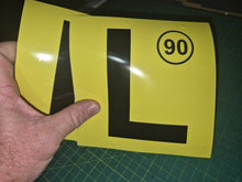 Load image into Gallery viewer, Yellow sign with a black 'L' and number 90 held by a hand on a green cutting mat.
