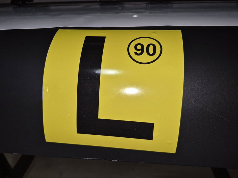 Yellow and black traffic sign with number 90 on a dark surface